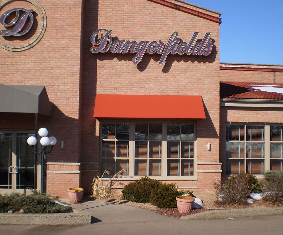 Dangerfields building front with D logo and clear face scripted channel letters over custom orange awning