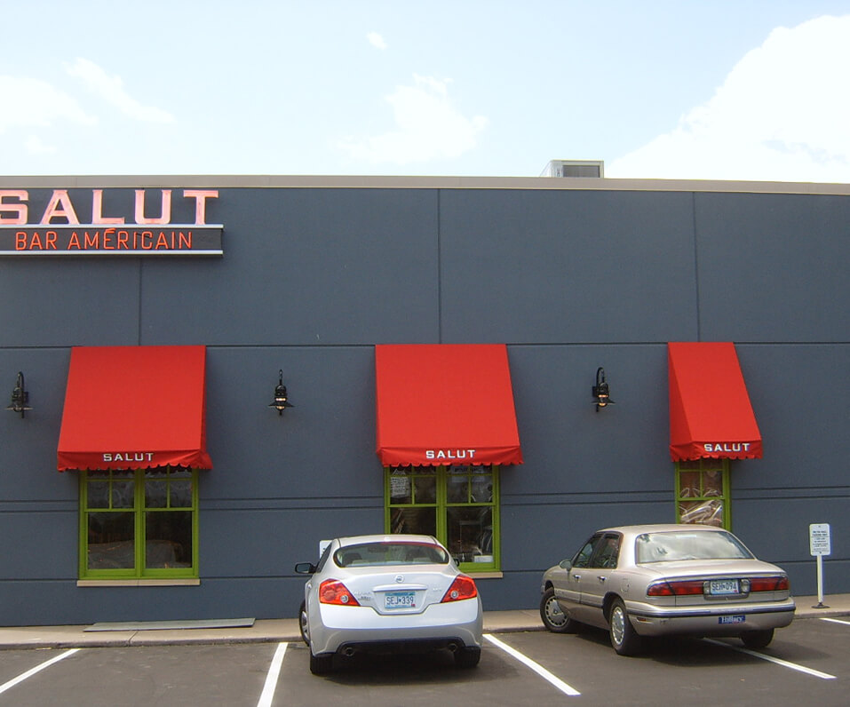 Salut Bar Americain Building with Red Awnings over green windows